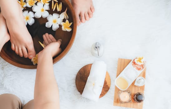 Woman indulges in blissful foot massage at luxurious spa salon while masseur give reflexology therapy in gentle day light ambiance resort or hotel foot spa. Quiescent