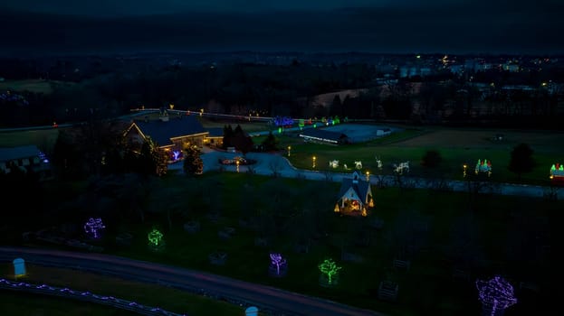 Overhead View Of A Rural Landscape At Twilight Featuring Decorative Holiday Lights On Trees And Structures, With A Small Chapel In The Foreground.