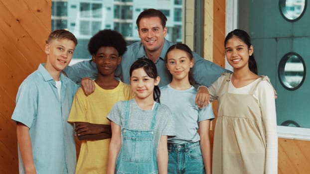 Happy teacher and diverse student standing while smilling to camera. Professional smart instructor with highschool children with mixed races in casual outfit pose at camera with cheerful. Edification.