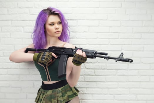 hot girl in a short sexy military skirt with a Kalashnikov assault rifle and a gun case on brick wall background copy paste