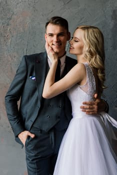 Cute wedding couple in the interior of a classic studio. They kiss and hug each other.