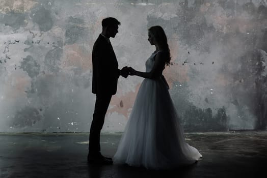 Cute wedding couple in the interior of a classic studio decorated. They kiss and hug each other.