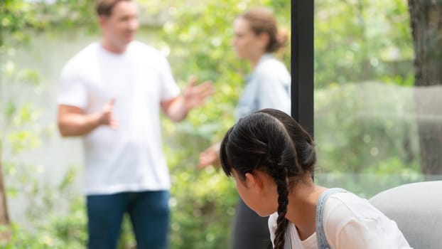 Stressed and unhappy young girl huddle in corner crying and sad while her parent arguing in background. Domestic violence at home and traumatic childhood develop to depression. Panorama Synchronos