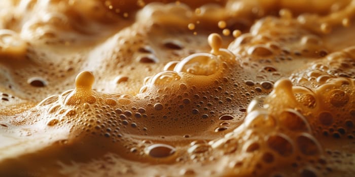 A close up, macro shot showing the bubbles and texture of a delicious, hot cup of brown coffee with a light layer of foam forming a pattern on top. Image has copy space.