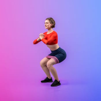 Full body length gaiety shot athletic and sporty young woman with fitness elastic resistance band in squat exercise posture on isolated background. Healthy active and body care lifestyle.