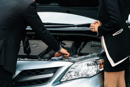 Man help woman fix the car problem. He pop up the car hood to repair the damaged part. uds