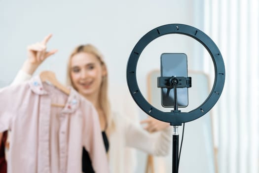 Young social medial content creator woman make fashion video. Blogger smiles to camera and light ring while making persuasive online clothing sell vlog to audience or follower. Blithe