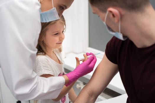 For fun, the nurse shows the girl how to administer the injections. The child performs the vaccine with the help of a nurse. A bold approach to children. Safe vaccination of children.