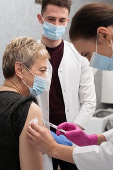 A young nurse injects a woman in her 50s with a new COVID19 vaccine. An injection with a new vaccine to support the body and increase resistance to infectious diseases.