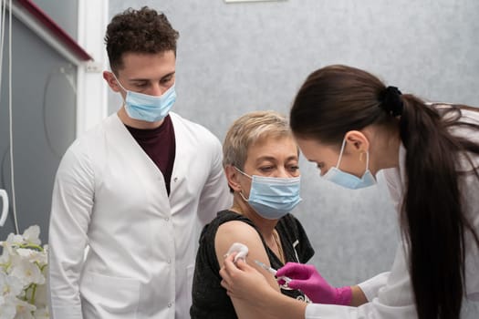 A young nurse injects a woman in her 50s with a new COVID19 vaccine. An injection with a new vaccine to support the body and increase resistance to infectious diseases.