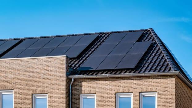 Newly built houses with black solar panels on the roof against a sunny sky Close up of new building with black solar panels. Zonnepanelen, Zonne energie, Translation: Solar panel, Sun Energy