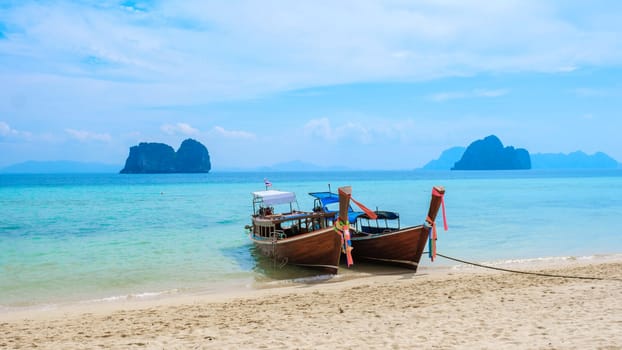 two Longtail boats on the beach of Koh Ngai island near Koh Lanta with soft white sand, and a turqouse colored ocean, Koh Ngai Trang Thailand
