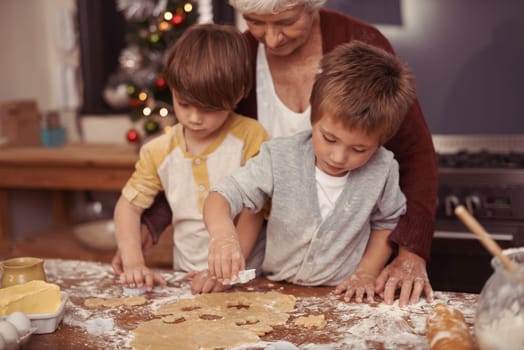 Learning, grandma and children in kitchen baking dessert or pastry. Education, kids and grandmother with cookie dough on table for quality time together in house or holiday, vacation and celebration