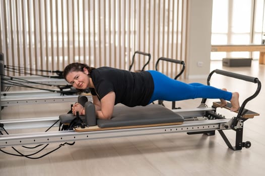 Overweight caucasian woman doing pilates exercises on a reformer