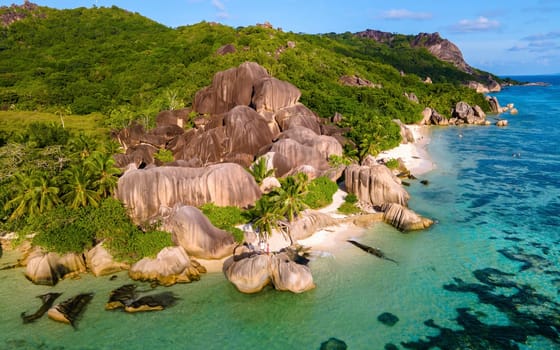 a couple of men and women walking at the beach during sunset on a luxury vacation. Anse Source d'Argent beach La Digue Island Seychelles, top view, drone view