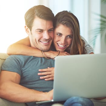 Laptop, happy and woman embracing man on sofa networking on social media, website or internet. Smile, love and female person hugging husband reading online blog with computer in living room at home
