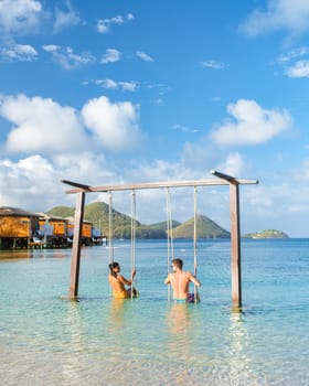 Couple in a swing on the beach of the tropical Island Saint Lucia or St Lucia Caribbean, man and woman tropical holiday vacation. men and women on a luxury vacation at the caribbean