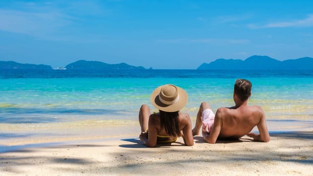 young couple of men and women lying down on a tropical beach during a luxury vacation in Thailand, diverse couple of caucasian man and Asian woman on vacation in Thailand, Koh Wai Island Trat Thailand