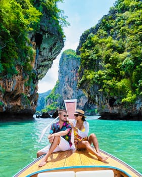 Luxury Longtail boat in Krabi Thailand, couple man, and woman on a trip to the tropical island 4 Island trip in Krabi Thailand. Asian woman and European man island hopping on vacation in Thailand.
