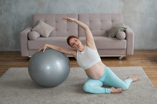 Pregnant woman doing side bends with a fitness ball at home