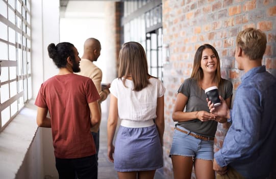 Students, men and women on campus friends, talking and standing together in corridor. Diversity, people and group in college for education, communication and discussion for conversation while smiling.