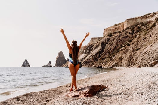 Woman beach vacation photo. A happy tourist in a blue bikini enjoying the scenic view of the sea and volcanic mountains while taking pictures to capture the memories of her travel adventure