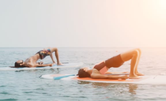 Woman sup yoga. Happy young sporty woman practising yoga pilates on paddle sup surfboard. Female stretching doing workout on sea water. Modern individual female outdoor summer sport activity