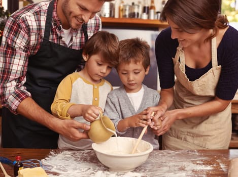 Family, smile and kids baking in kitchen, learning or happy boys bonding together with parents in home. Father, mother or children cooking with flour, food and brothers pour milk in bowl at table.