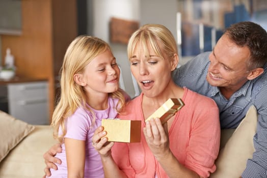 Surprise, father and child with present for mom on birthday or opening a box on mothers day. Family, gift and dad with kid in home giving woman unique package of gold to show gratitude, care or love.