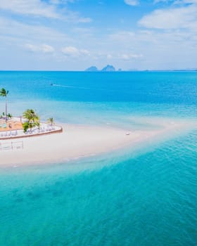 Drone top view at Koh Muk tropical island turqouse colored ocean Koh Mook Trang Thailand, a couple on a sandbar in the ocean on a sunny day, top vertical view