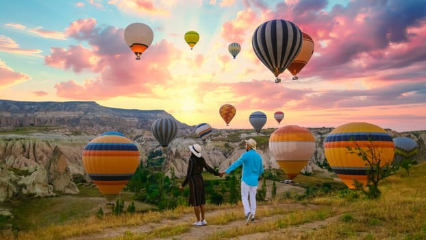 Kapadokya Cappadocia Turkey, a happy young couple during sunrise watching the hot air balloons of Kapadokya Cappadocia Turkey during vacation, a diverse couple of an Asian woman and caucasian man