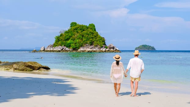 rear view of a couple of men and women on vacation in Thailand walking at the beach on a sunny day, you a diverse couple of Asian woman and European man, Koh Lipe Island Southern Thailand