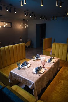 This image showcases an elegant restaurant interior with a table set for four, yellow booths, and ambient lighting, ideal for fine dining or a romantic dinner for two.