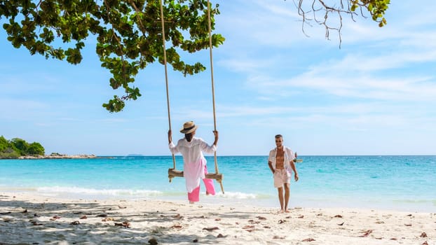 A couple of men and women at a swing on the beach of Koh Samet Island Rayong Thailand, a couple on honeymoon in Thailand having fun on the beach with a swing on a sunny day