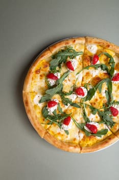 Freshly baked pizza with strawberries, cream cheese and arugula on a white plate. view from above.