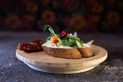 A delicious and healthy open-faced sandwich with cream cheese, smoked salmon, microgreens, and sun-dried tomato on a wooden board. Perfect for a light lunch or snack. Isolated on white background.