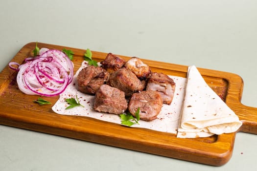 Lamb skewers with grilled vegetables, pita bread on wooden board. Made with lamb, cooked on grill, seasoned spices, warm soft pita.