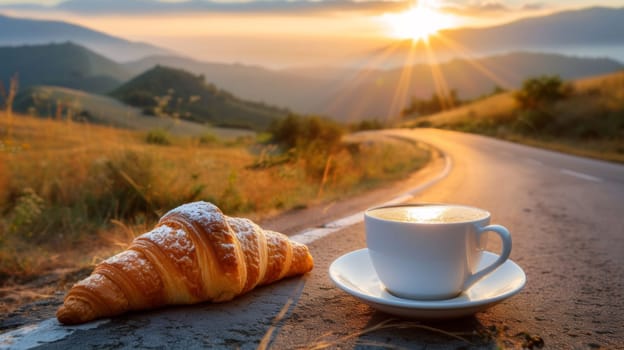 A cup of coffee and a croissant on the side of road