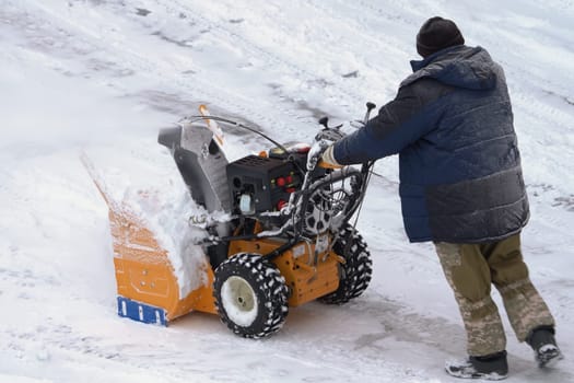KAMCHATKA, RUSSIA - DEC 28, 2023: A man is using a snow blower to clear snow from a winter road after a winter storm, assisted by a snow thrower