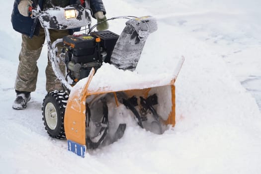 KAMCHATKA, RUSSIA - DEC 28, 2023: After the winter cyclone, man is using a snow blower machine to clear the snow from the driveway. This involves throwing the snow away from the road