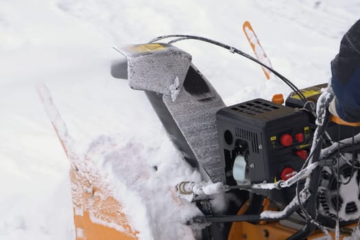 KAMCHATKA, RUSSIA - DEC 28, 2023: A man is using a snow blower to clear snow from driveway after winter storm, removing snow from road, throwing it away, with goal of clearing snow after storm passes