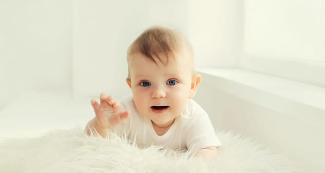 Portrait of cute little baby crawling on the floor in white room at home