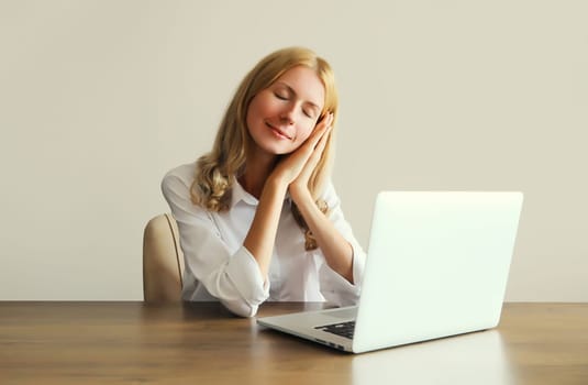 Tired overworked sleeping woman employee while working with laptop sitting at desk in office in morning