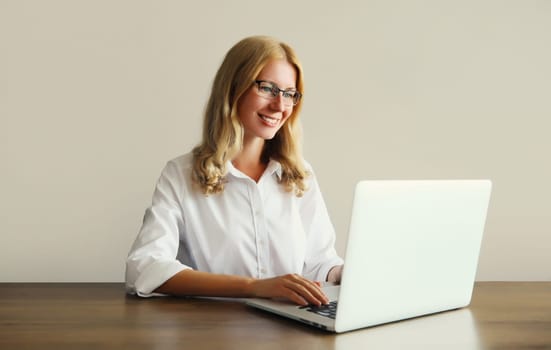 Happy young woman working with laptop sitting at desk in office or home