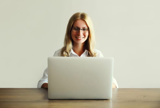 Happy young woman working with laptop sitting at desk in office or home