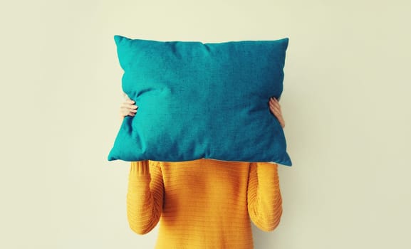 Healthy sleep, woman covering her head with colorful soft pillow holding in hands at home in morning