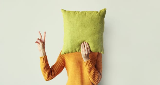 Healthy sleep, woman covering her head with colorful soft pillow holding in hands at home in morning