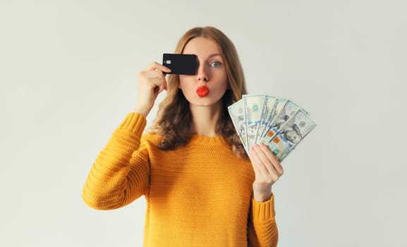 Portrait of happy smiling young woman holding plastic credit bank card and cash money in dollar bills