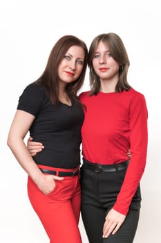 Woman mother 43-years-old dressed in black t-shirt and red trousers, daughter 14-year-old on contrary in red t-shirt and black trousers. Studio shot on white background. Part of photo series