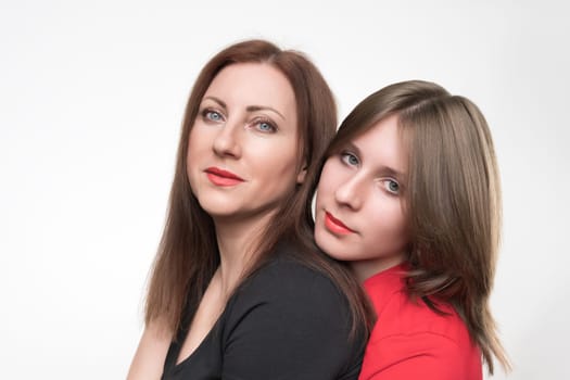 Portrait of woman mother and daughter looking at camera. Mom in black t-shirt and teenager in red t-shirt. Studio shot on white background. Part of photo series